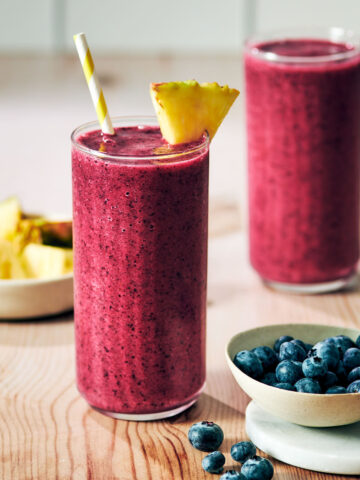Pineapple Blueberry Smoothies in glasses with a pineapple garnish.