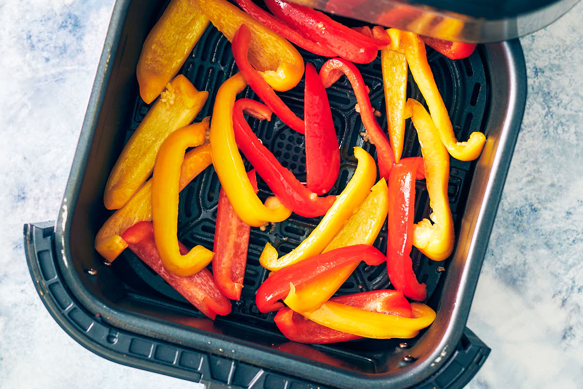 Bell peppers in an air fryer basket before baking.
