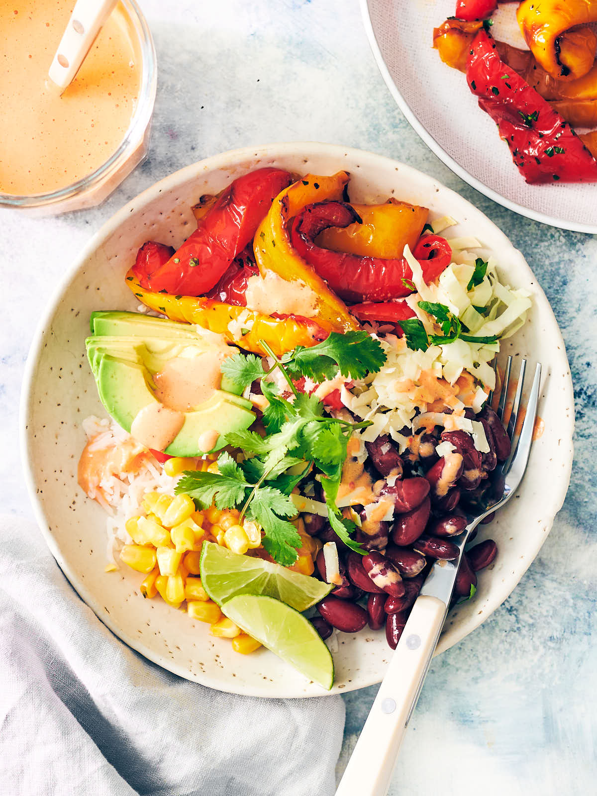 Burrito bowl with air fryer bell peppers, avocado, beans, cheese, and cilantro.