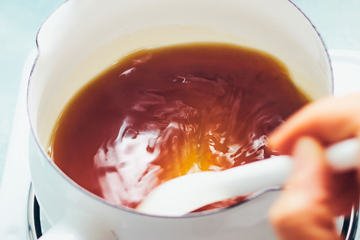 Stirring water and brown sugar in a saucepan to make a homemade maple syrup alternative.
