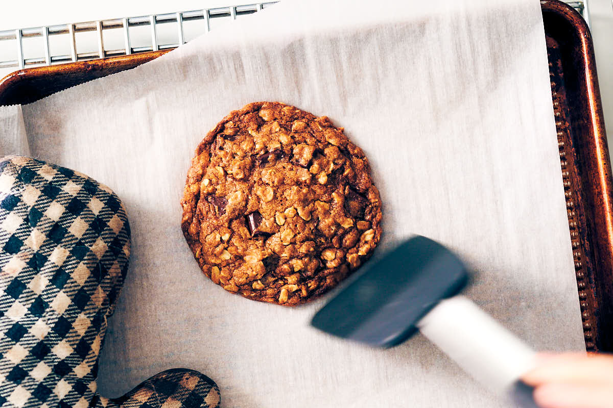 Single serving oatmeal cookie on a baking sheet with a spatula.