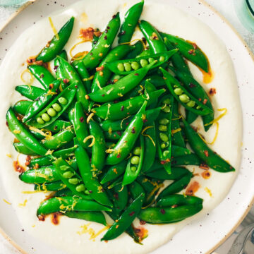 A plate of Snap Pea Salad on whipped feta on a table.