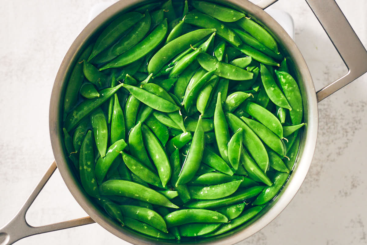 Boiling sugar snap peas in a pot of hot water.