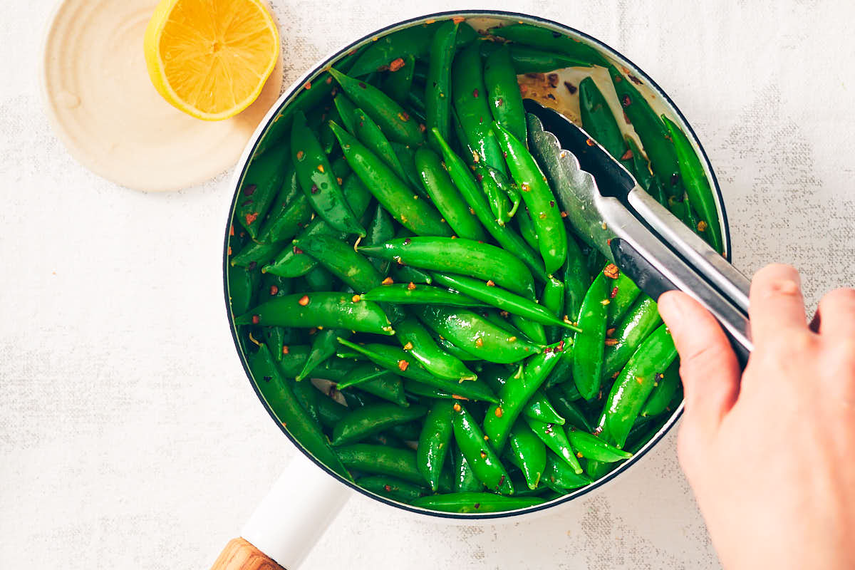 Tossing sugar snap peas in chili garlic oil for Snap Pea Salad.