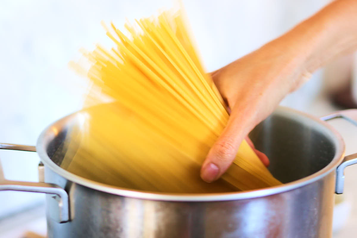 Adding pasta to a pot of boiling water to cook.