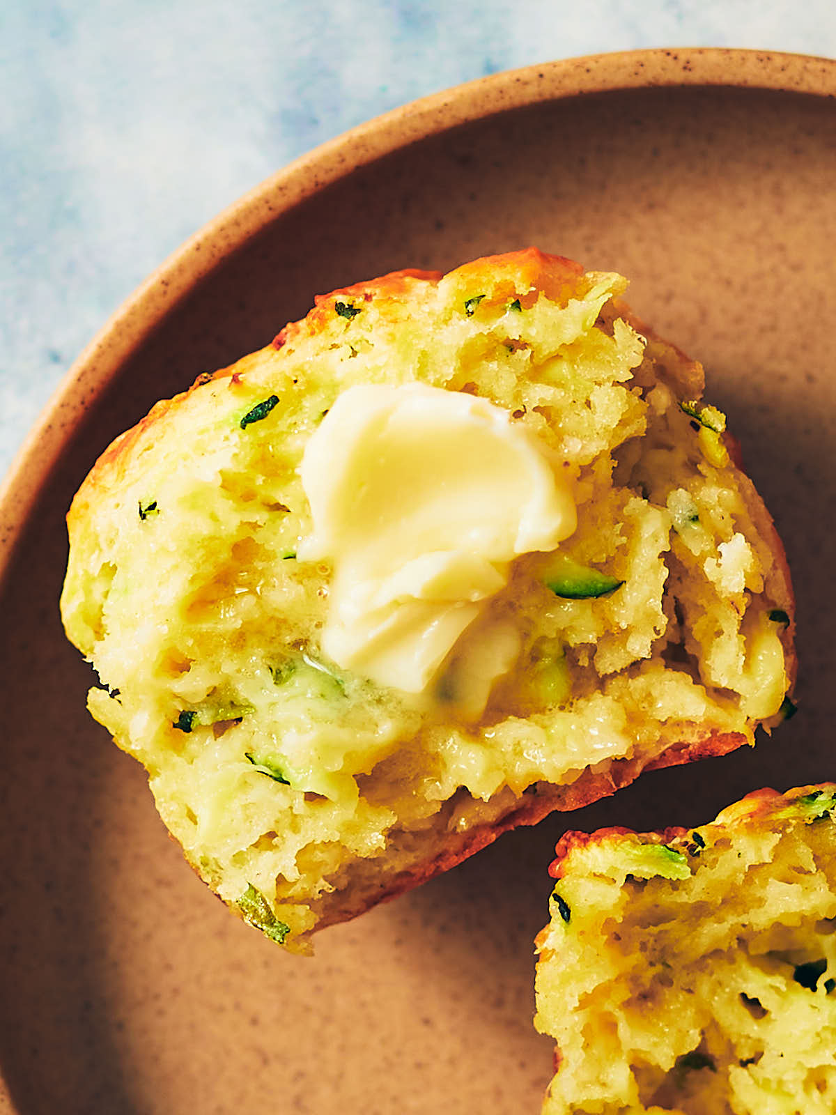 Savory zucchini muffin with butter melting on top.