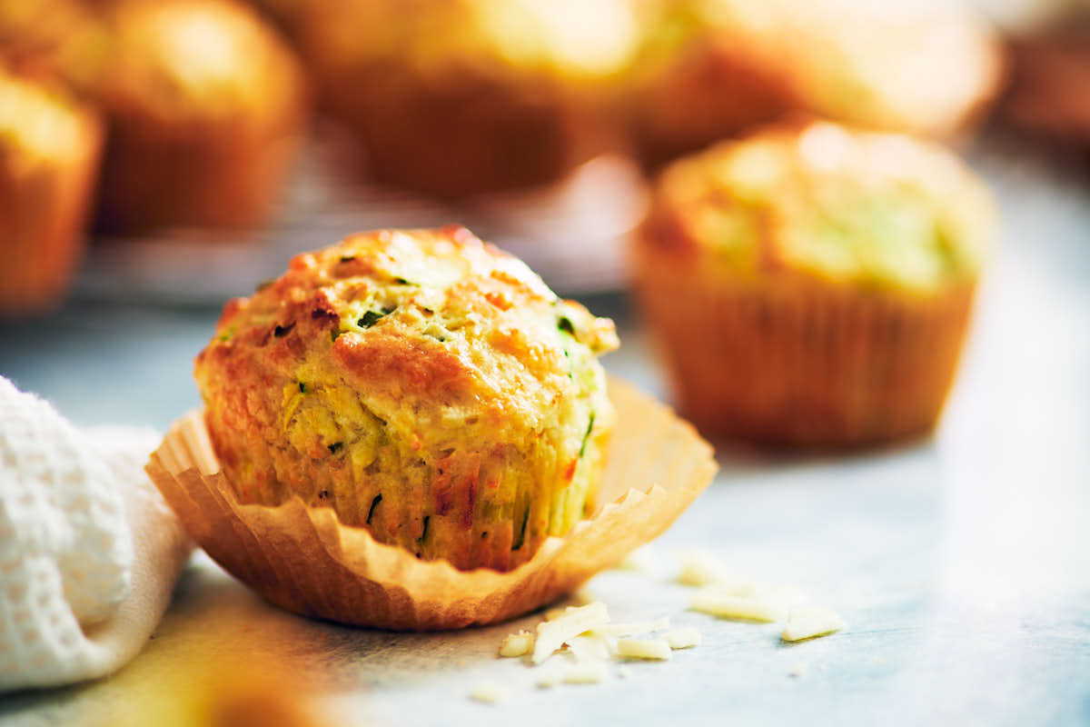 Savory zucchini mmuffins with cheese on a kitchen counter.