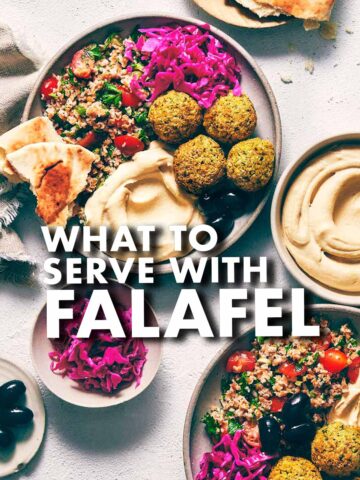 Falafel on a plate with pickled red cabbage, hummus, pita, and salad.