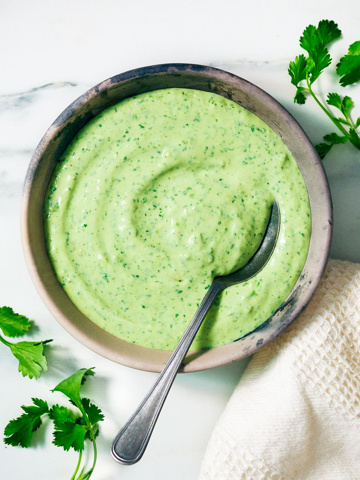 Creamy Cilantro Yogurt Sauce in a bowl with a spoon.