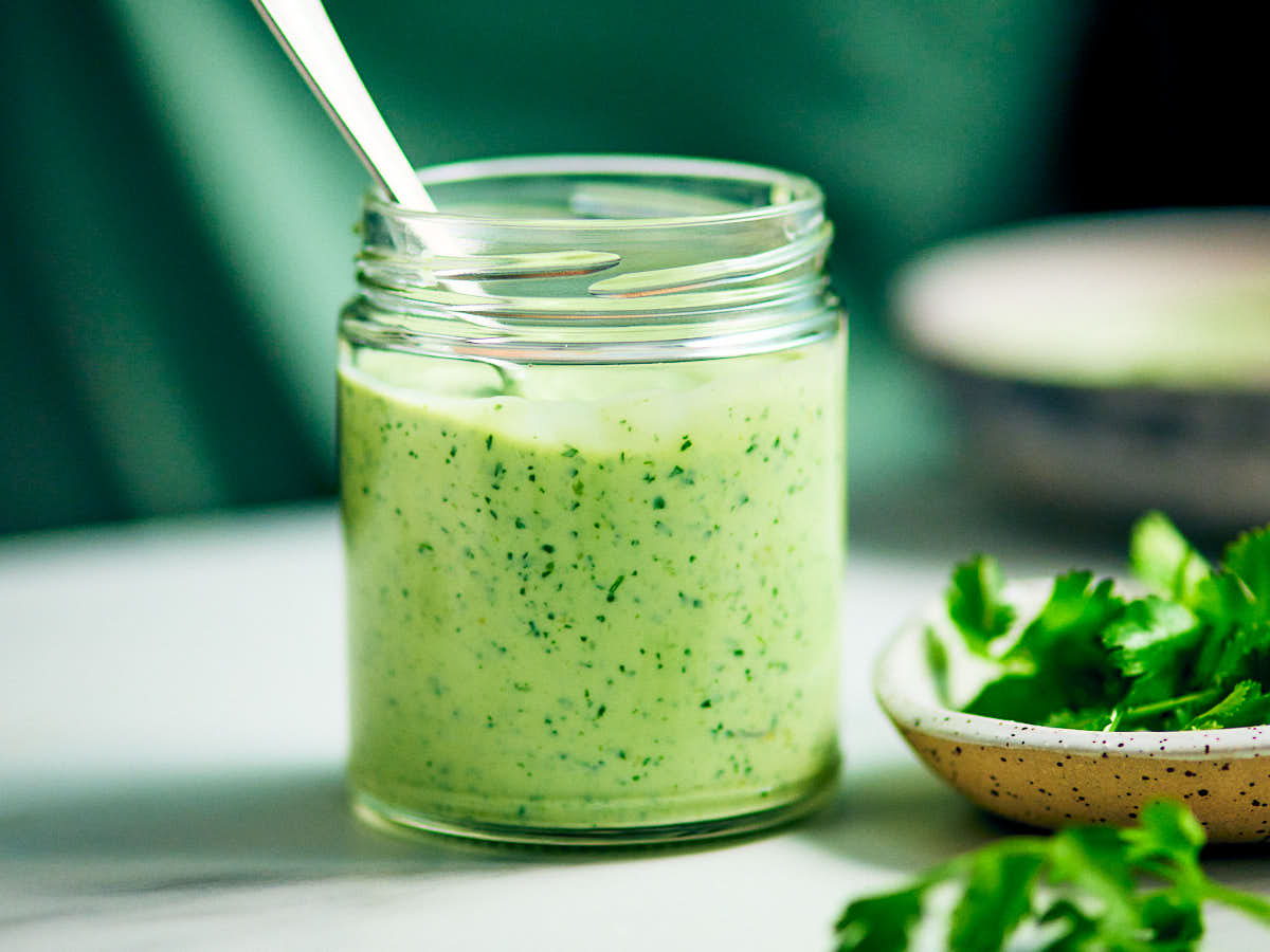 Cilantro Yogurt Sauce with Greek yogurt in a glass jar on a counter.