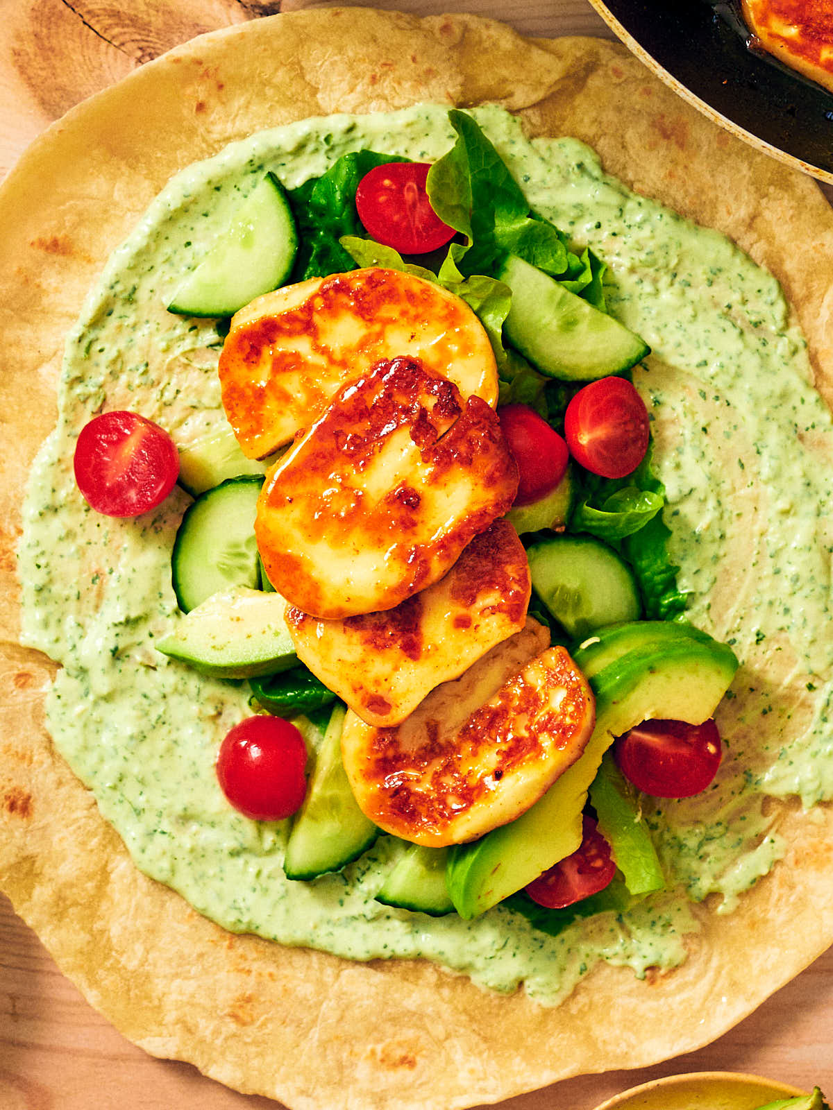 Seared halloumi, creamy cilantro sauce, and fresh veggies on a wrap.