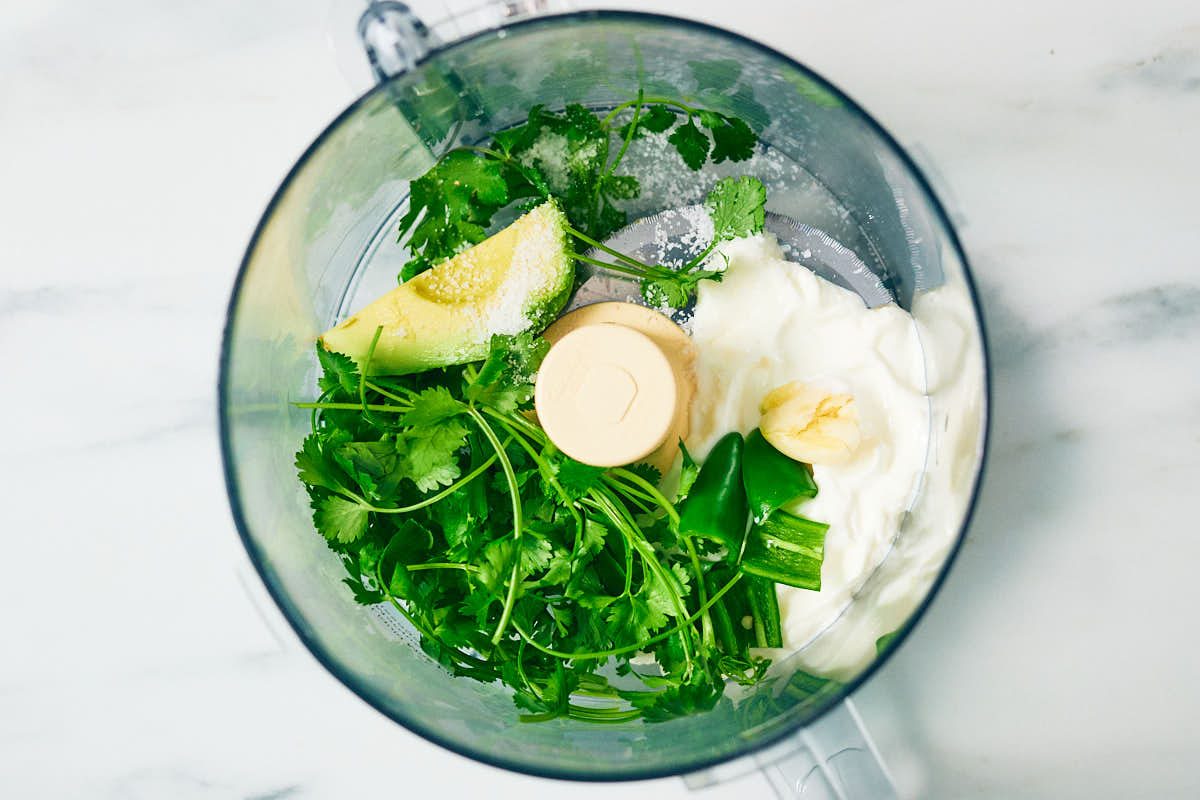 Cilantro, avocado, and yogurt in a food processor to make cilantro sauce.