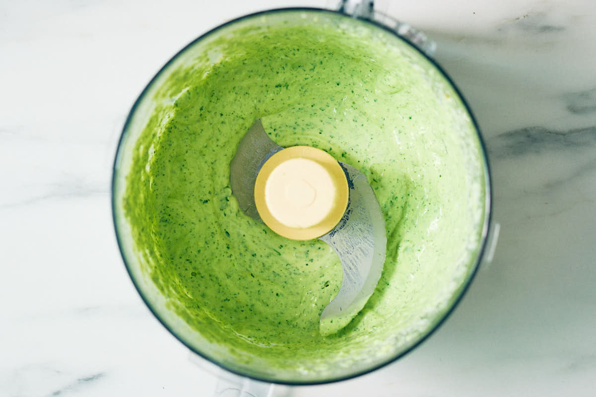 Cilantro yogurt sauce in a food processor container.