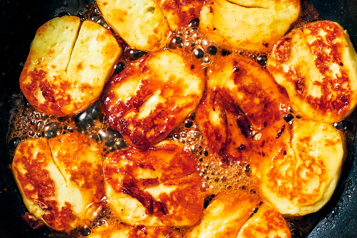 Seared halloumi cheese with hot honey bubbling in a frying pan.