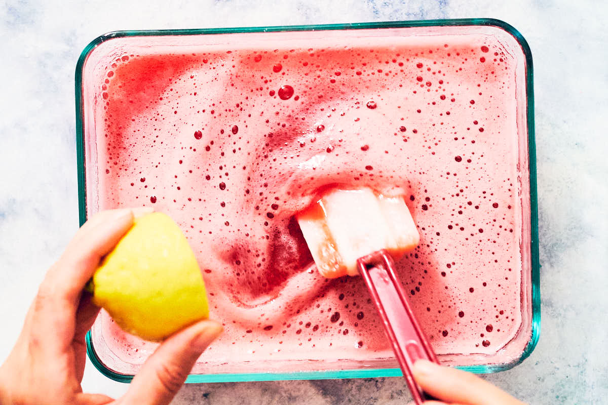 Adding fresh lemon juice to strawberry rhubarb granita mixture before freezing.