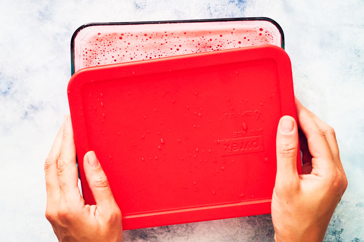 A lid being put over a glass container before freezing.