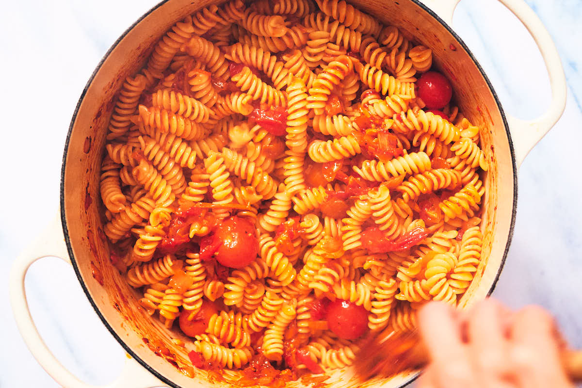 Tomato pasta being stirred in a pot.