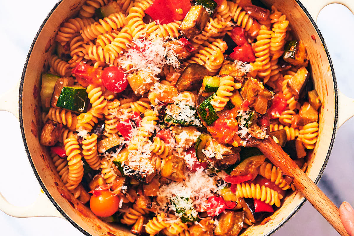 Roasted vegetables and tomato pasta in a pot with Parmesan cheese.