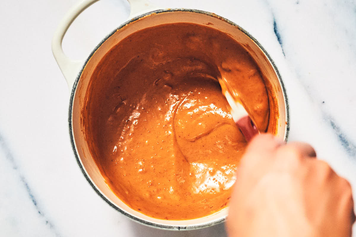 Warming peanut sauce in a pot for vegan satay.