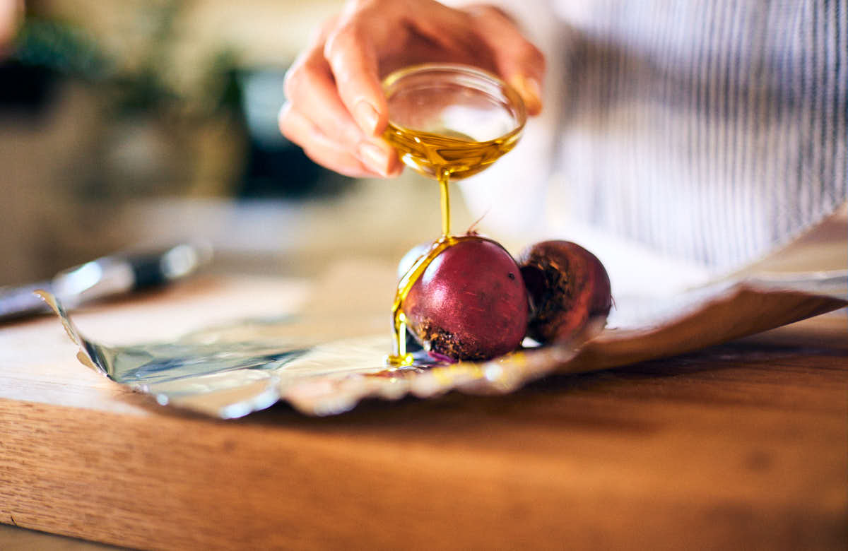 Olive oil being drizzled over red beets for air fryer beets.