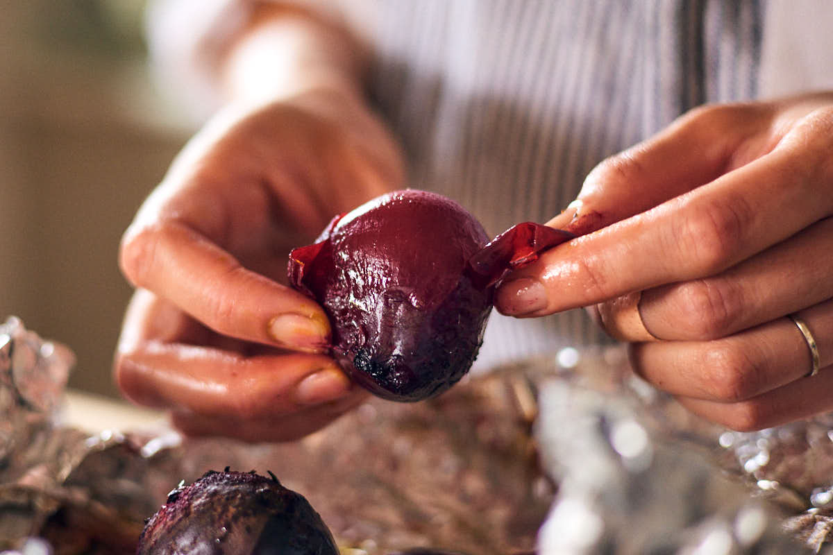 A woman peeling skins of air fryer beets after roasting.