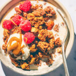 High Protein Air Fryer Granola in a bowl with yogurt, milk, berries, almond butter.