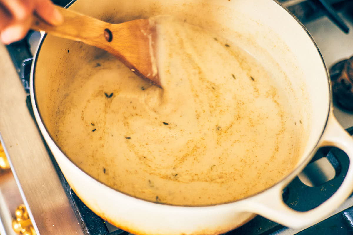 Garlic herb pasta sauce being stirred in a pot.