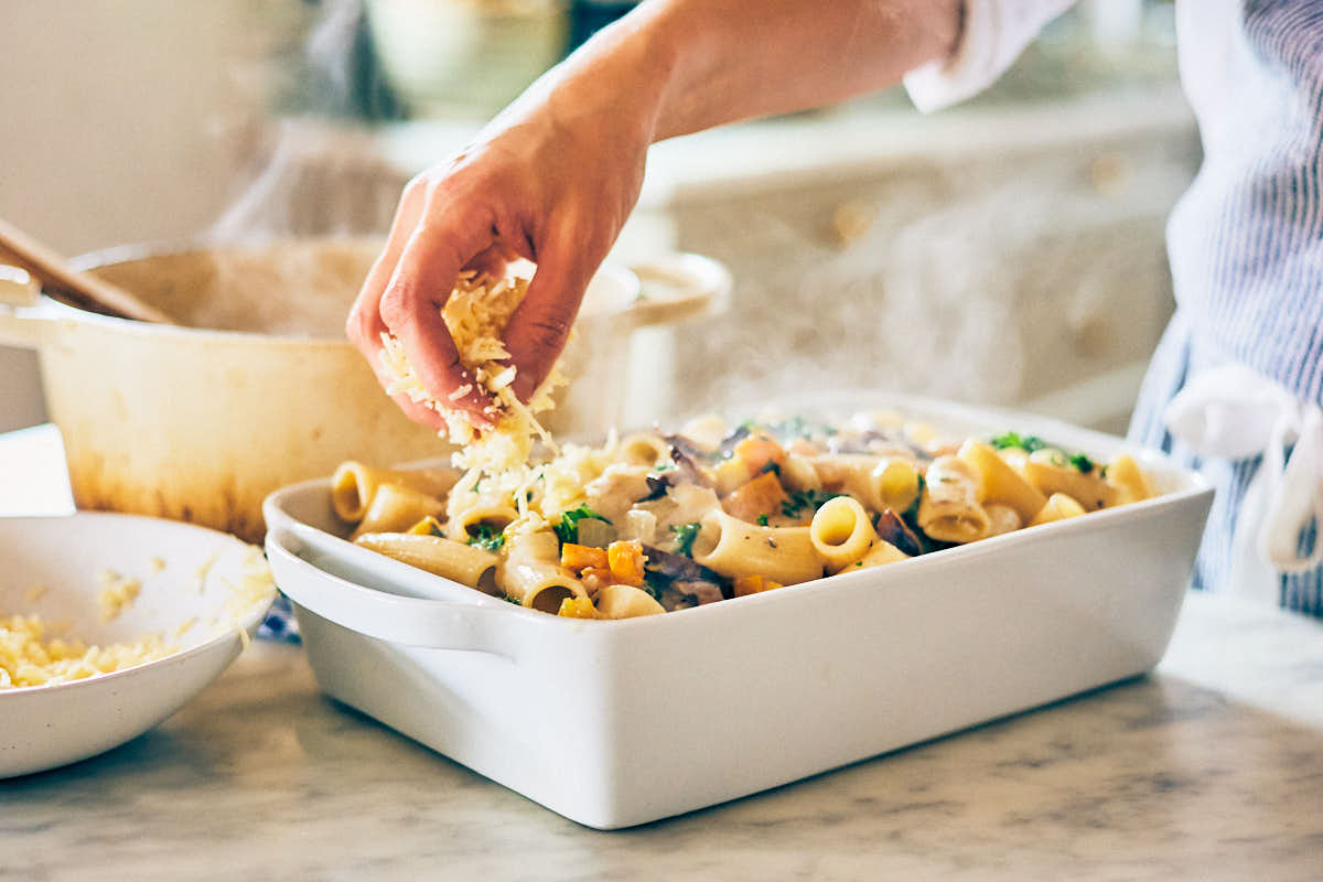 Butternut squash pasta being topped with cheese in a casserole dish.