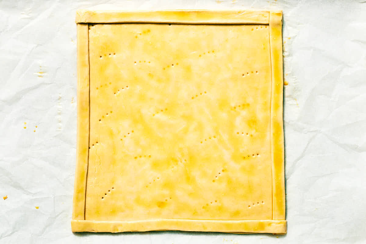 Unbaked puff pastry on a parchment lined baking sheet.