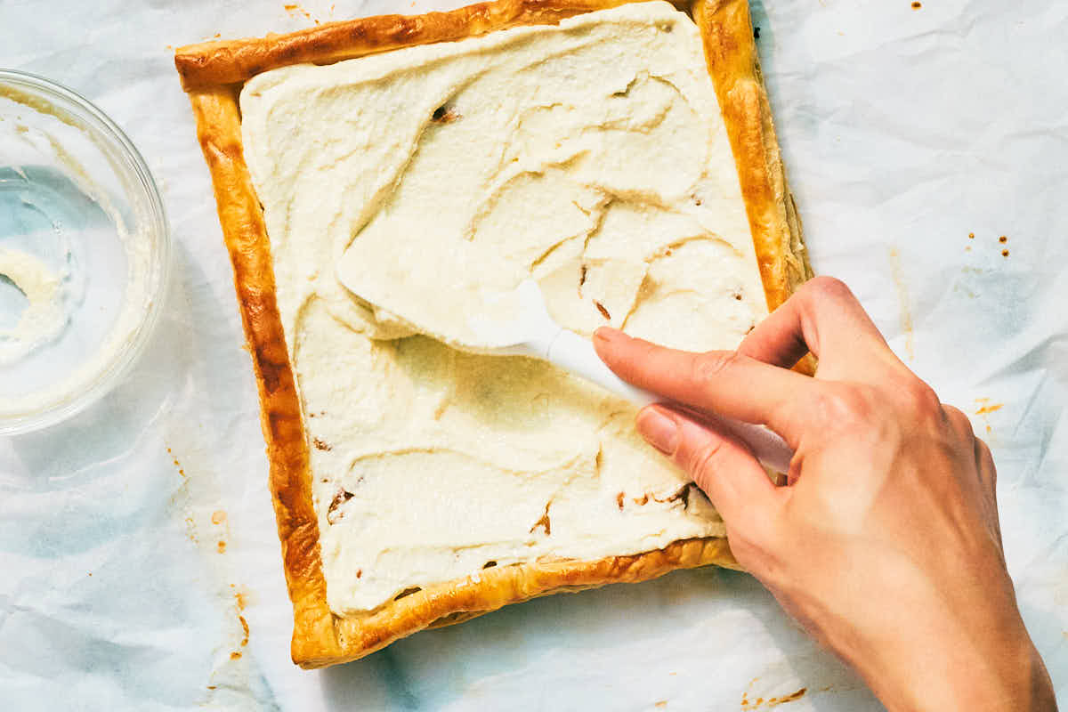 Whipped feta being spread over puff pastry for a squash tart.