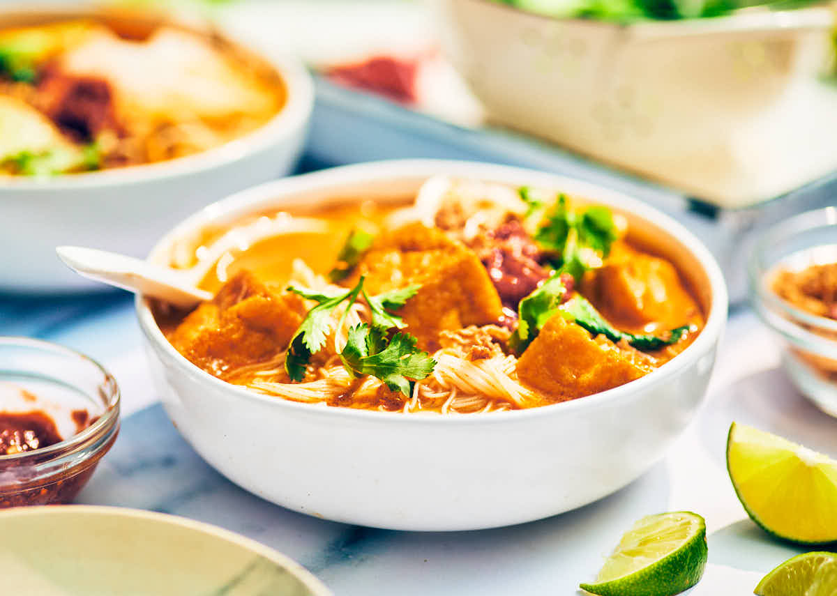 Vegan laksa noodle soup with tofu and coconut in a bowl.