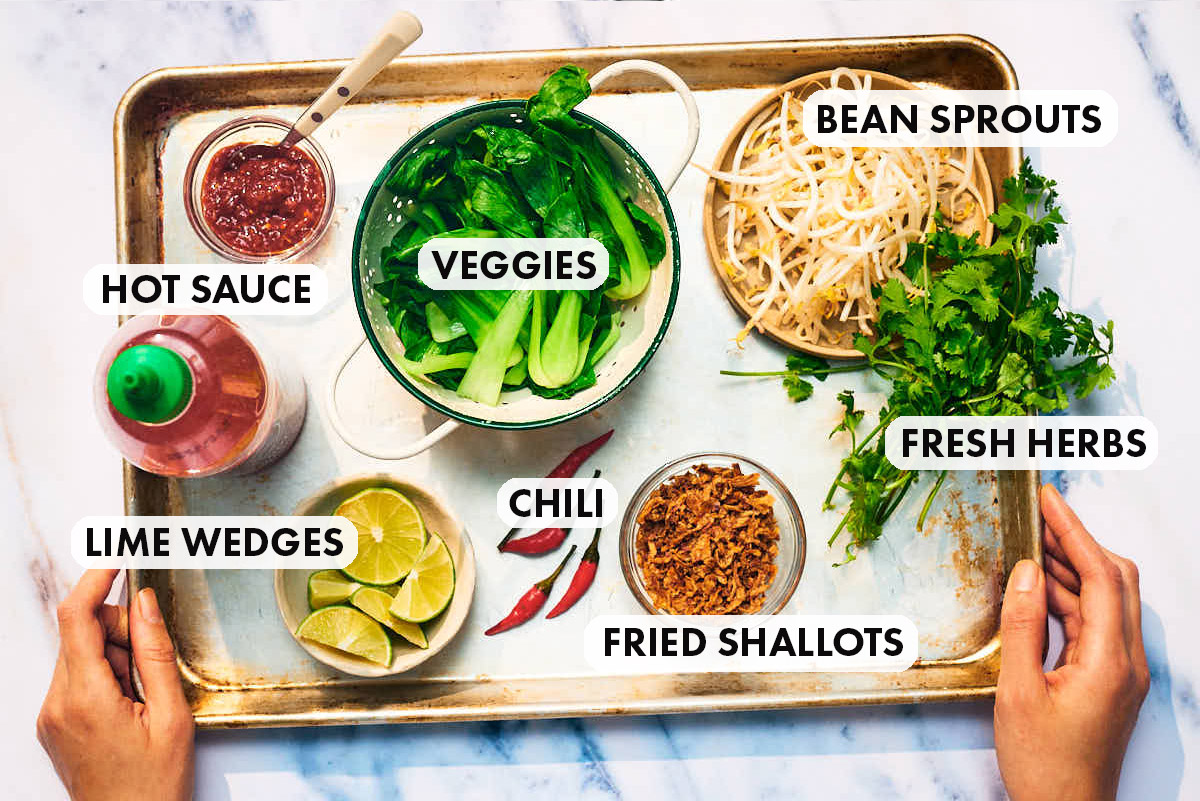 Laksa soup toppings, including bean sprouts, herbs, fried shallots, on a tray.