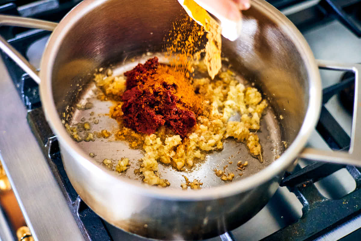 Saute garlic and ginger, then add curry paste and spices.