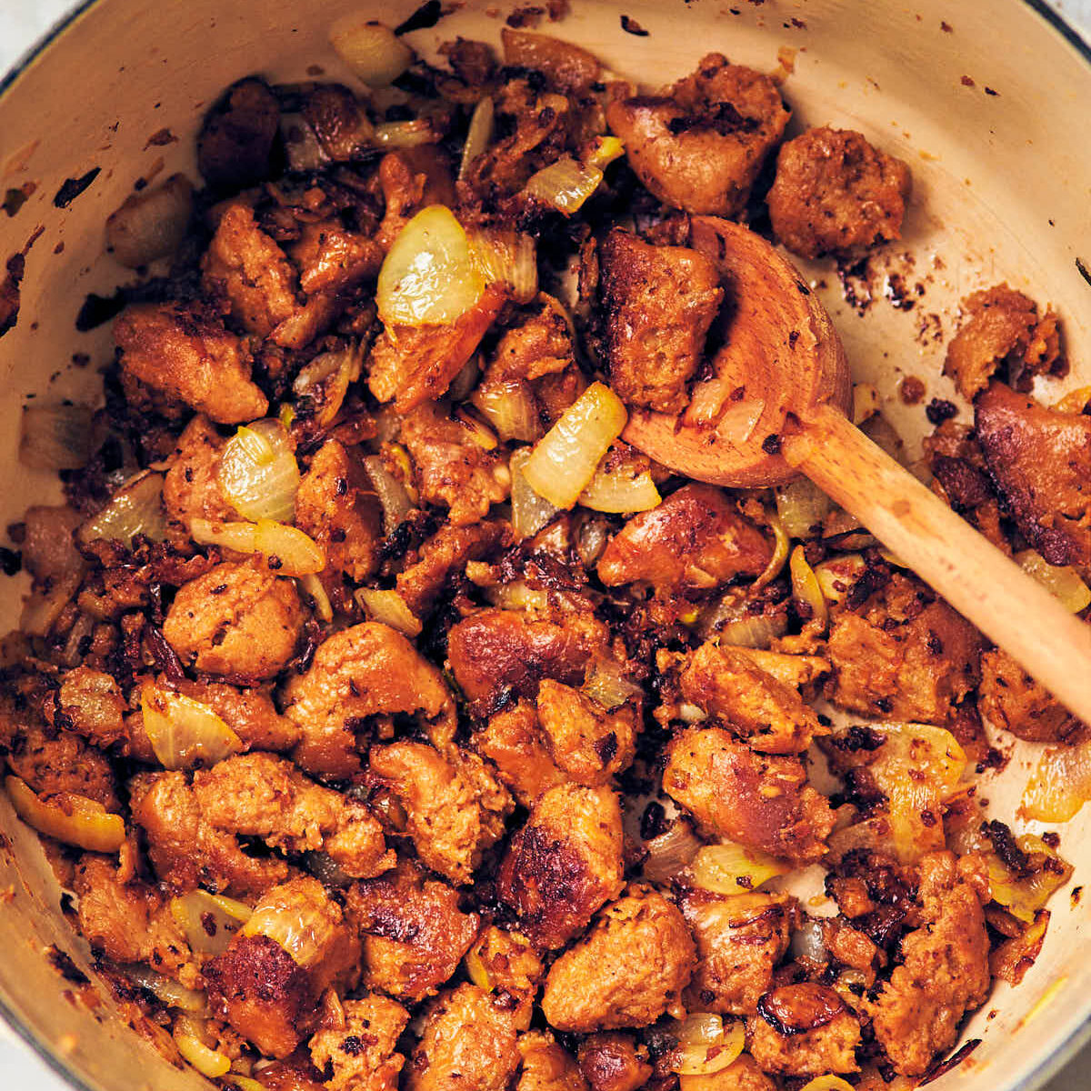 Crispy brown crumbled plant based sausage with onion in a Dutch oven.