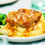 Crispy holiday tofu with panko on a plate with mashed potatoes and gravy.