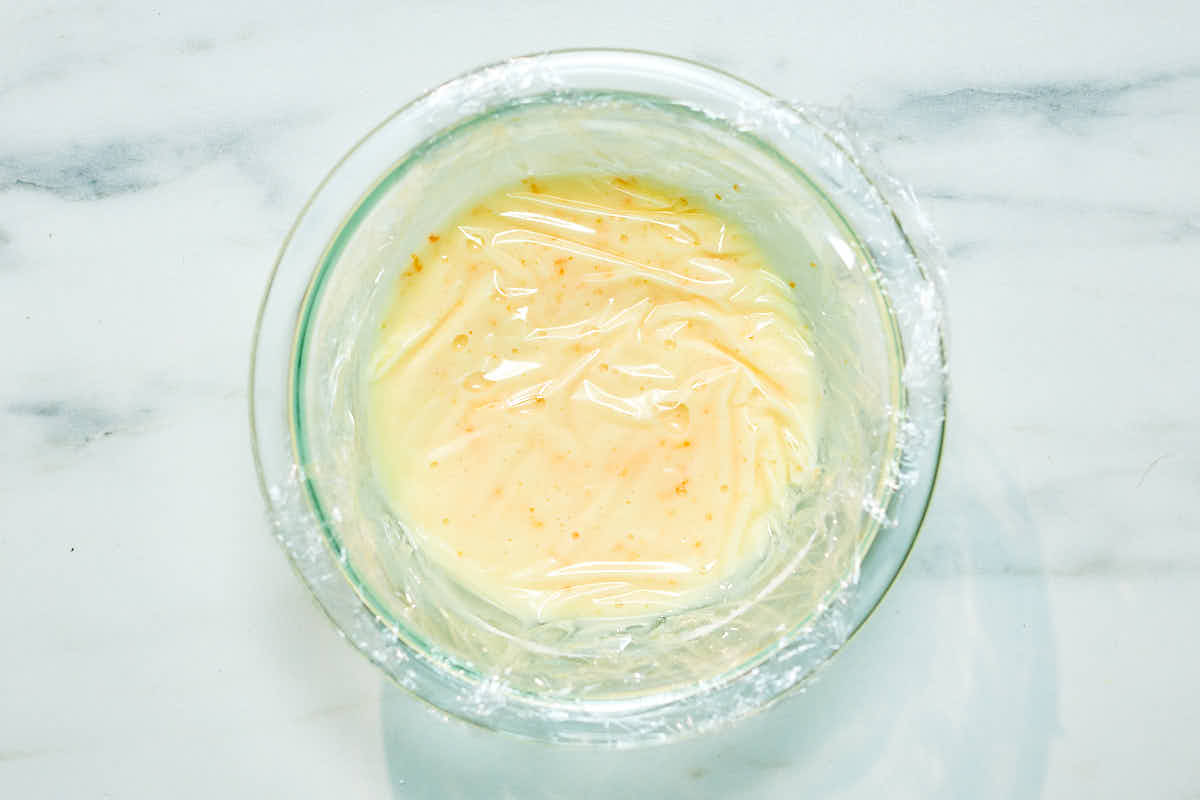 Plastic wrap pressed on top of icing in a bowl to stop icing from hardening.