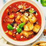 Roasted Eggplant and Tomato Soup with croutons and basil in a bowl.