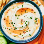 Whipped Feta Dip with Hot Honey in a bowl served with pita and vegetables.