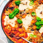Crispy Eggplant Parmesan Baked Gnocchi in a skillet topped with basil.