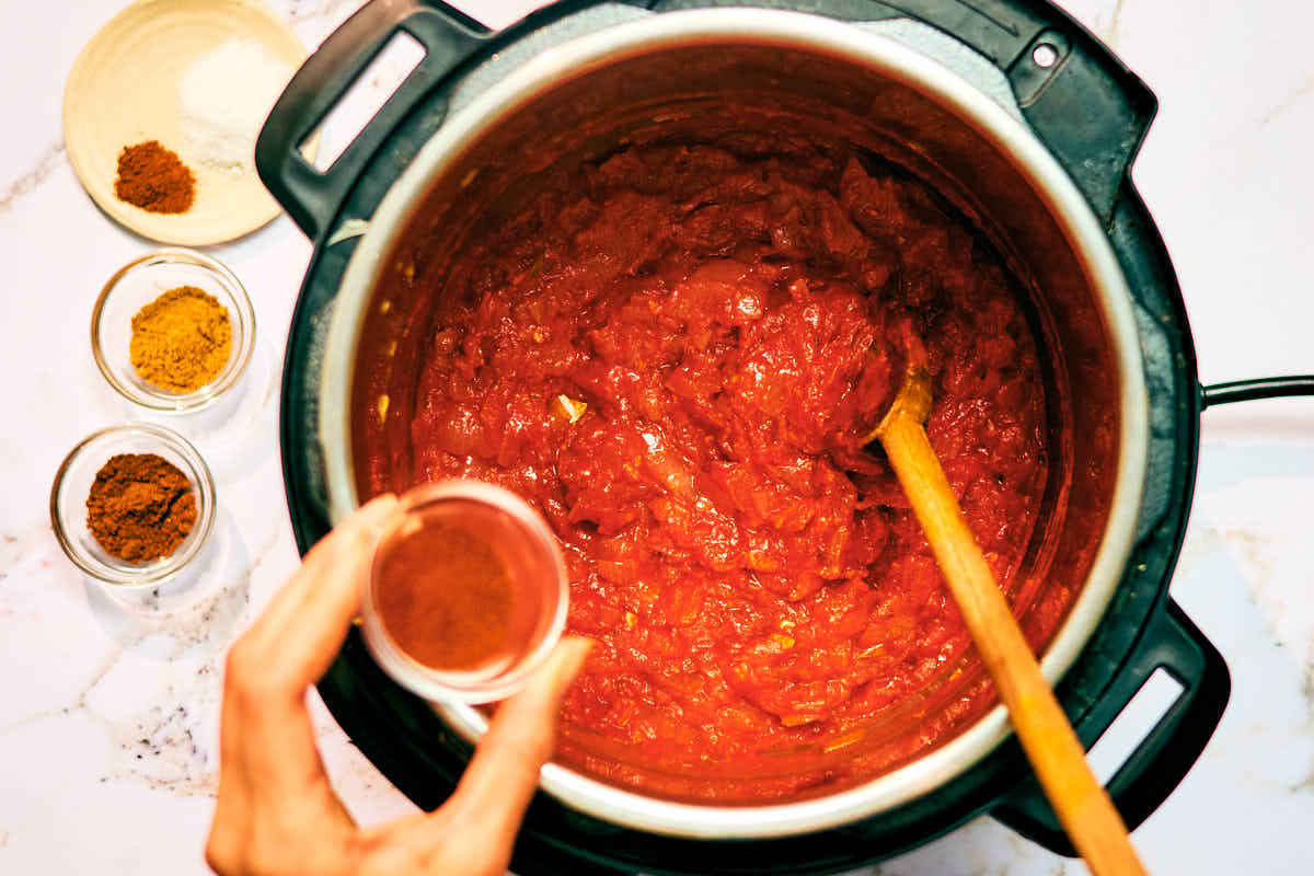Spices being added to tomato masala for Instant Pot Dal Makhani.