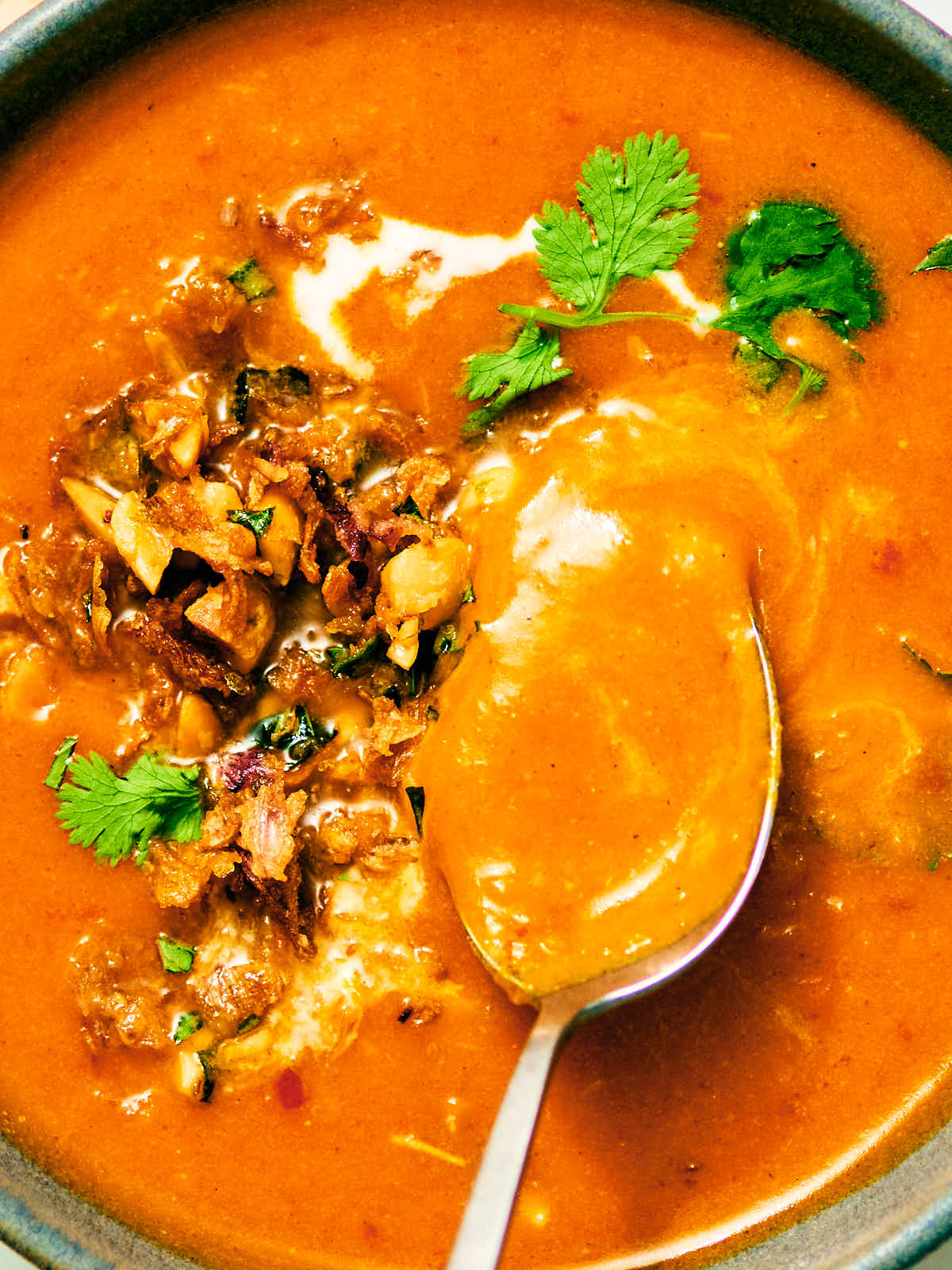 Kabocha squash soup in a bowl with coconut milk, Peanut Lime Crunch topping, and cilantro.