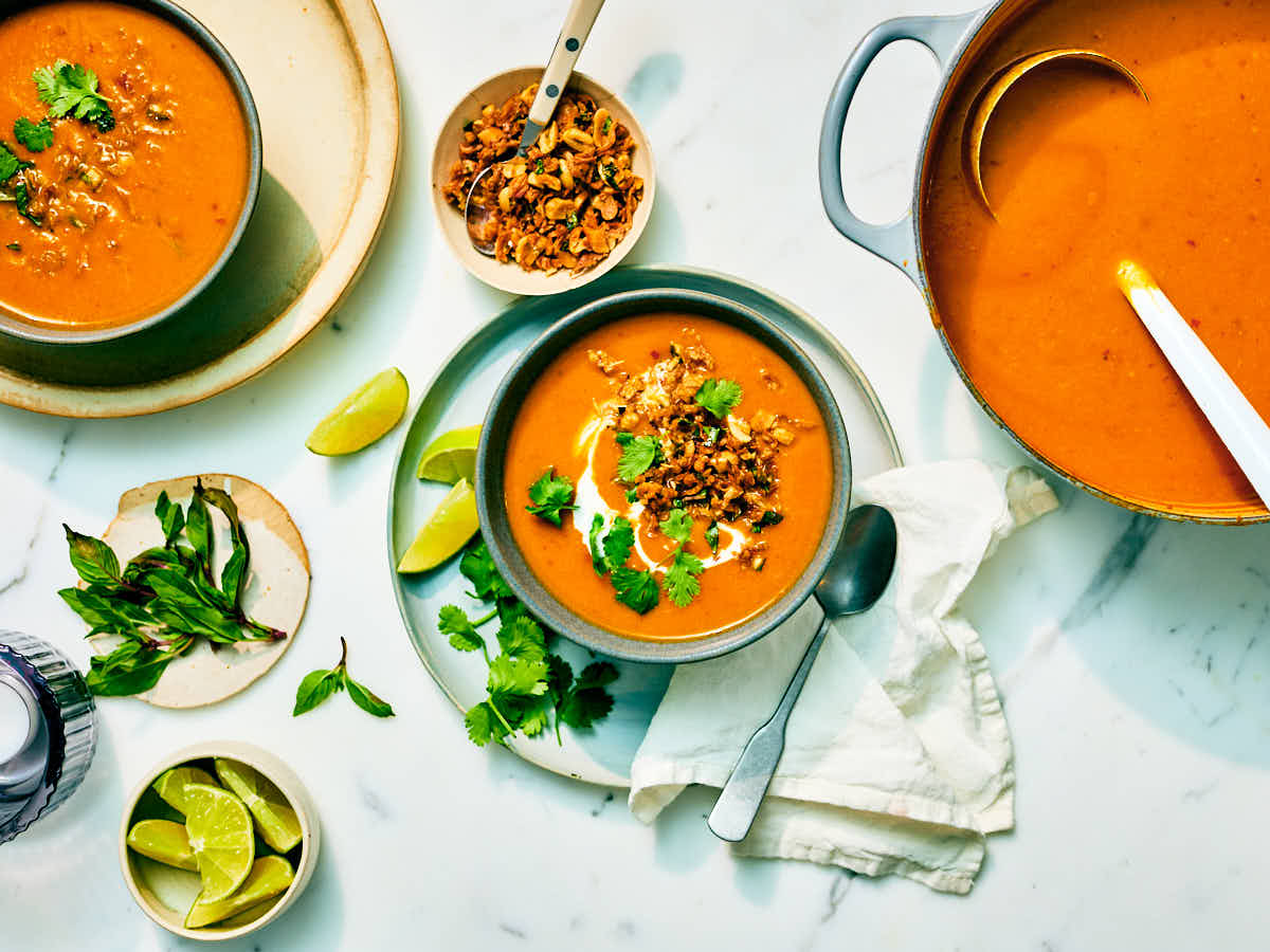 A pot and bowls of Kabocha Squash Soup on a marble counter with toppings.