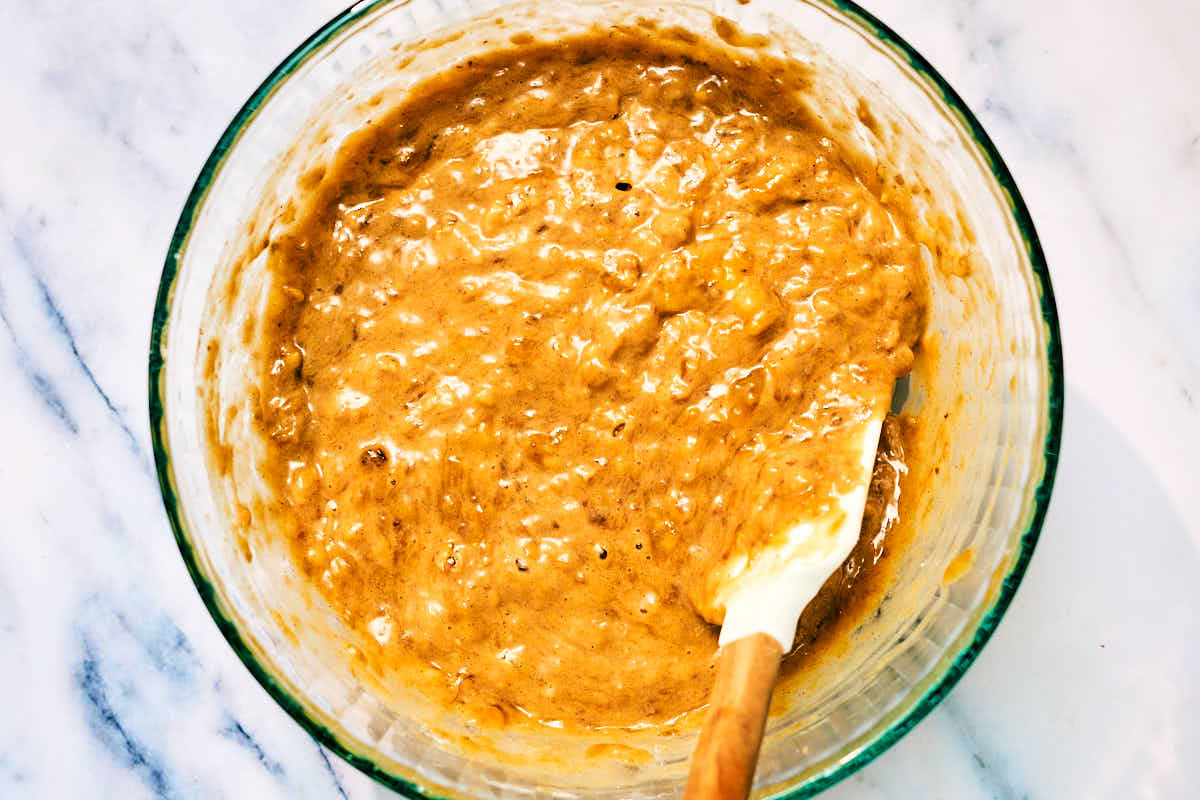 Banana nut bread mini muffin batter in a bowl with spatula.