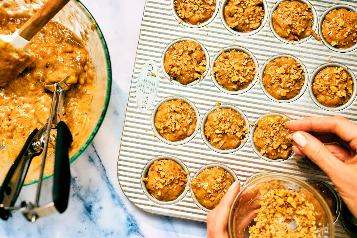 Banana nut bread being prepared in a mini muffin tin before baking.