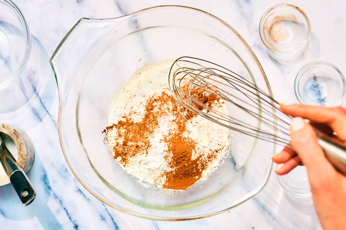 Dry ingredients being whisked in a bowl for banana walnut mini muffins.