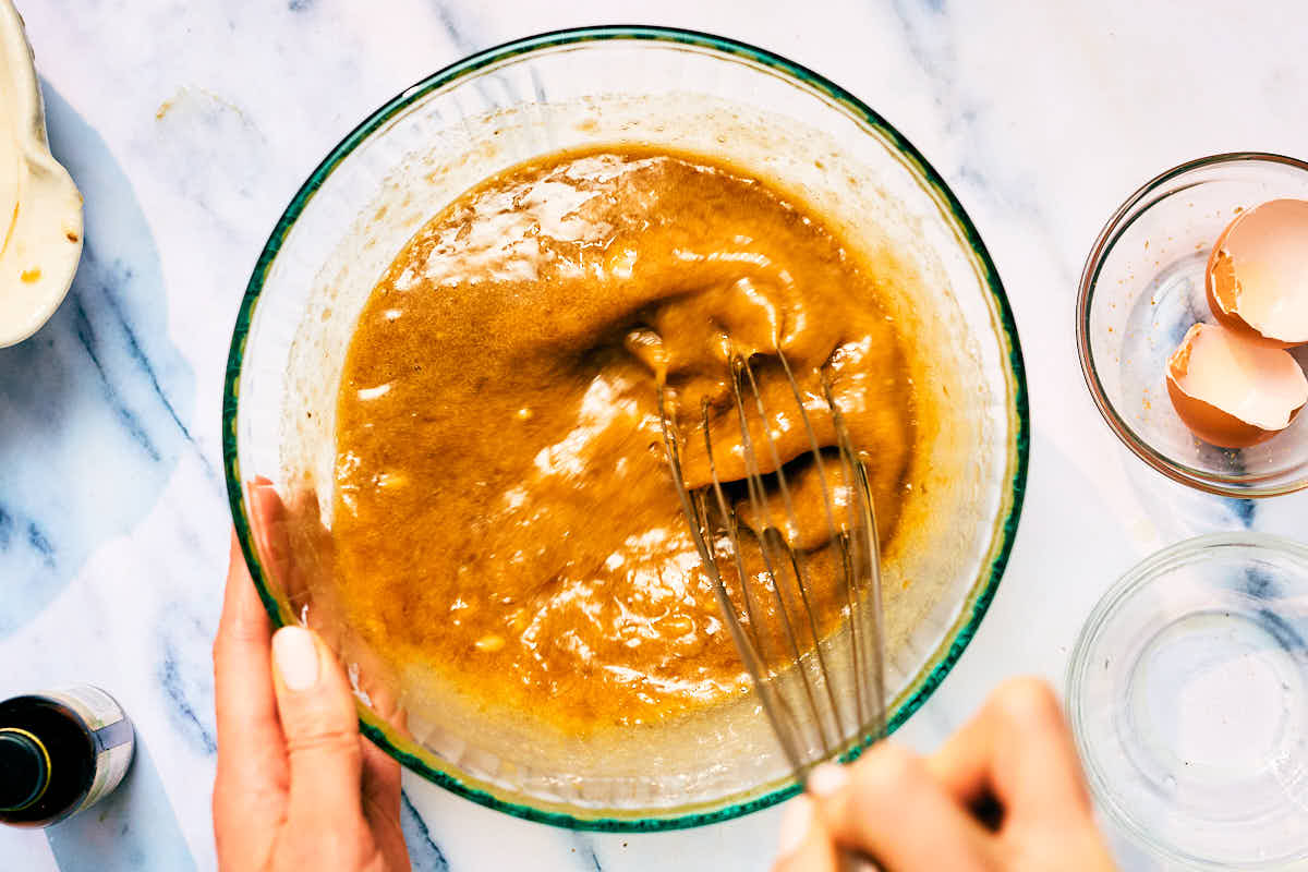 Wet ingredients being whisked in a bowl for banana nut bread mini muffins.
