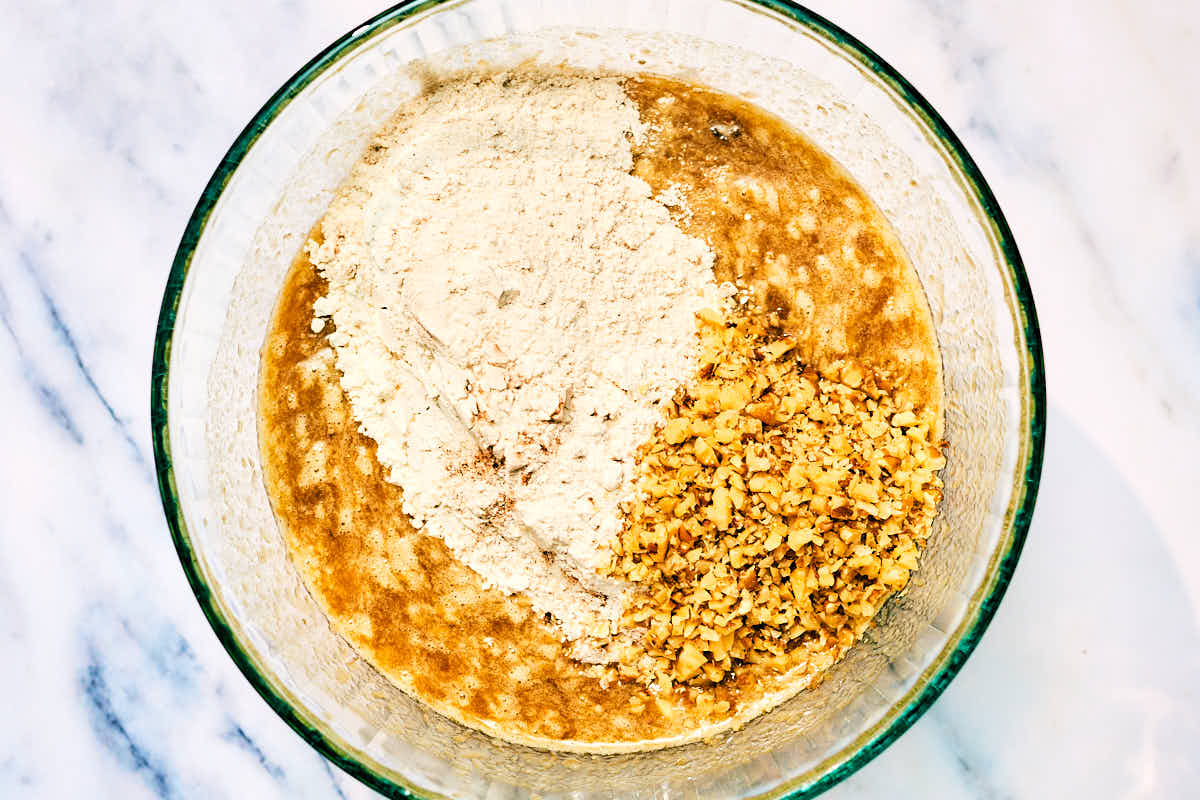 Dry and wet ingredients and walnuts in a bowl for mini muffins.