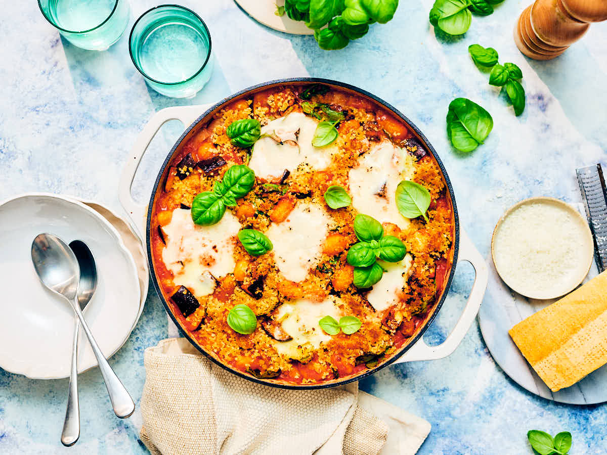 Baked Gnocchi with tomato sauce, mozzarella, eggplant, crispy panko, and basil in a skillet.