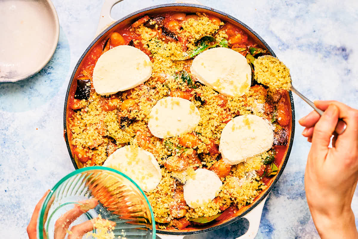 Crispy panko being scattered over Tomato Gnocchi Bake with mozzarella.