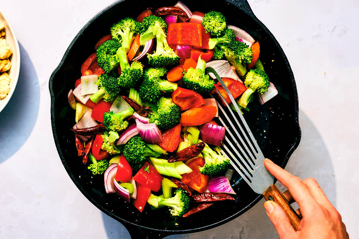 Fresh vegetables being stir fried in a skillet for Kung Pao Vegetables.